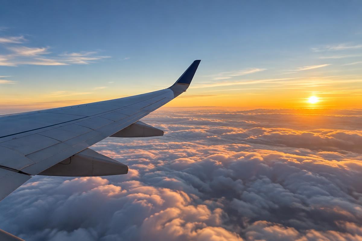 View of an airplane wing above the clouds at sunrise